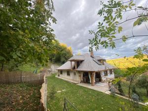 une petite maison blanche avec un toit sur une cour dans l'établissement Casa cu șindrilă, à Vălenii de Munte