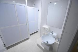 a white bathroom with a toilet and a shower at Pousada Paris Hostelli in Penedo