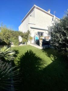 een huis met een tuin met groen gras bij Villa à 10 minutes de Nîmes in Marguerittes