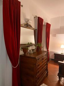 a room with red curtains and a dresser with a mirror at Veleia Romana B&B in Rustigazzo