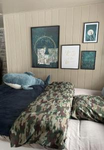 1 dormitorio con 1 cama con almohadas y fotografías de camuflaje en Koselig enmannsom i tømmerhus, inkl morgenkaffe en Eidsvoll