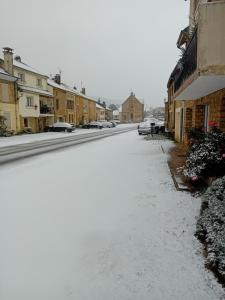 una calle cubierta de nieve en una ciudad con edificios en "Chez la Joe", en Thélonne