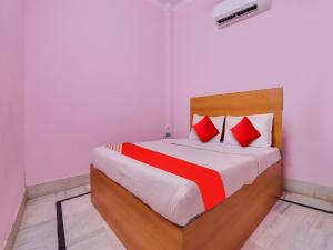 Hotel Yug Residency في حاريدوار: غرفة نوم بسرير كبير ومخدات حمراء