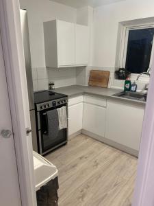 a kitchen with white cabinets and a stove at Cosy Three Bed, Lewisham in London