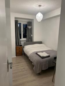 um quarto com uma cama e um lustre em Cosy Three Bed, Lewisham em Londres