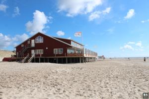 Un edificio rojo en la playa junto a la arena. en Lila aan zee - Recreatiepark de Watersnip, en Petten