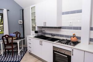 a kitchen with white cabinets and a sink and a table at Seloko Guest Cottage in Polokwane