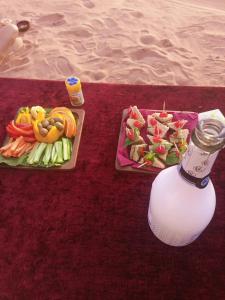 einen Tisch mit zwei Teller Essen und einer Flasche in der Unterkunft Alarb Quiet Camp in Wadi Rum