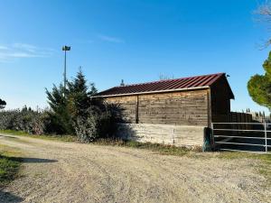 un antiguo granero al lado de un camino de tierra en Les Appartement du Mas - RUBIS, en Aigues-Mortes