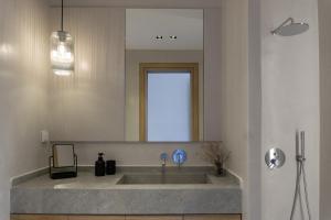 a bathroom with a sink and a large mirror at enδόtera chios apartments in Chios
