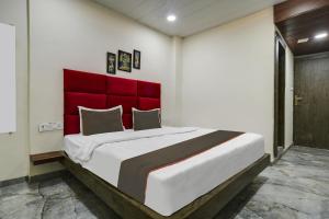 a bedroom with a large bed with a red headboard at Hotel DR Green in Dewās