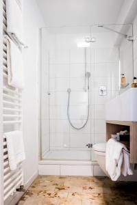 uma casa de banho branca com um chuveiro e um WC. em Hotel Hofgut Hohenkarpfen em Hausen ob Verena