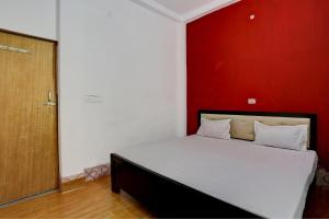 a bed in a room with a red wall at HOTEL SS PARADISE in Lucknow