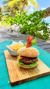 una hamburguesa y papas fritas en una mesa con un perro en Pronoia Casa de Playa, en Mahahual