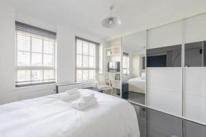 ロンドンにあるCosy Studio in Bethnal Greenの白いベッドルーム(白い大型ベッド1台、白いタオル2枚付)