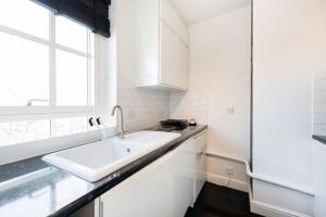 a white kitchen with a sink and a window at Cosy Studio in Bethnal Green in London