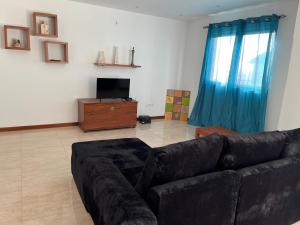 a living room with a black couch and a television at Nerys House in São Filipe