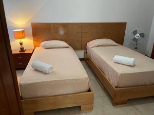two beds in a bedroom with a lamp and a night stand at Nerys House in São Filipe