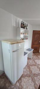 una cocina blanca con botellas de vino en una estantería en Residencial Vitor Studio 1 en São José dos Pinhais