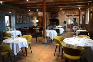 a restaurant with white tables and yellow chairs at Art'Hotel & SPA Le Potin Gourmand in Cluny