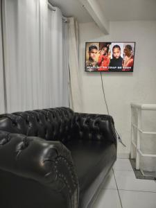 ein schwarzes Ledersofa im Wohnzimmer mit einem TV in der Unterkunft AP da Cris cabo frio in Cabo Frio