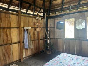 Habitación con paredes de madera, cama y ventana. en Punta Arena EcoHostal and EcoFit – Your Eco-Friendly Oasis en Playa Punta Arena