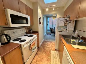 a kitchen with a stove and a sink and a microwave at Penthouses of Beach Ave in Vancouver