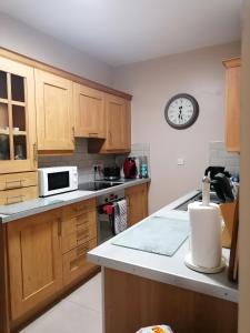 uma cozinha com armários de madeira e um relógio na parede em The Beeches em Newry