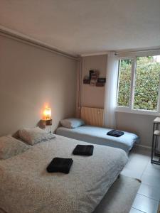 two beds sitting in a room with a window at Lagny Cocon Evasion Cosy en ville in Lagny