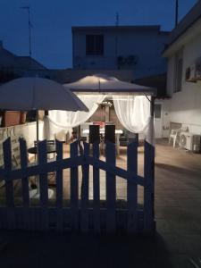 Bari PaleseにあるAngelo's Beach Houseの傘・テーブル・椅子二脚の柵