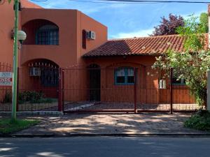 an orange house with a fence in front of it at Casa máximo confort con oficina in Campana