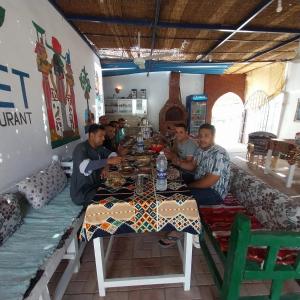 un grupo de hombres sentados en una mesa en un restaurante en Villa golden life apartments, new property with pool access, en Luxor