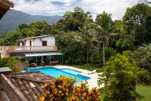 uma villa com piscina e montanhas ao fundo em Recanto da Rose Guesthouse em Caraguatatuba
