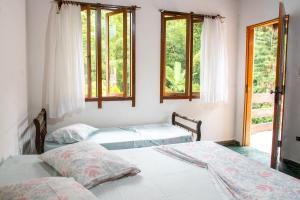 2 Betten in einem Zimmer mit 2 Fenstern in der Unterkunft Recanto da Rose Guesthouse in Caraguatatuba
