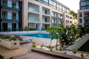 an apartment complex with a swimming pool in front of a building at Embasy Gardens by Rosy Apartments in Accra