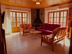 ToloríuにあるCal Pujol by Rural Houseの紫色のソファと椅子が備わるリビングルーム