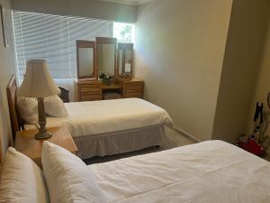 a bedroom with two beds and a lamp and a mirror at Ripplewood in Vereeniging