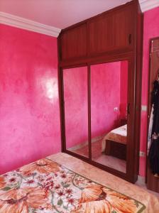 a pink bedroom with a mirror and a bed at Al fajar2 in Alimadene