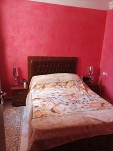 a bedroom with a bed with a red wall at Al fajar2 in Alimadene