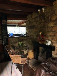 a table and chairs in a room with a stone wall at Chalés Serra do Trovão in Lavras Novas