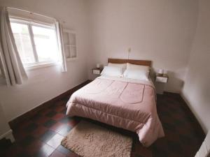1 dormitorio con 1 cama con ventana y alfombra en Hospedaje DCB en Capilla del Monte