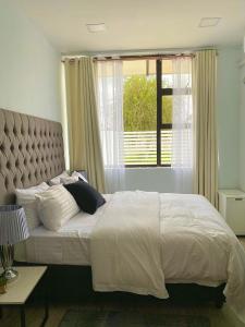 a bedroom with a large bed with a large window at White House Residences in Lusaka