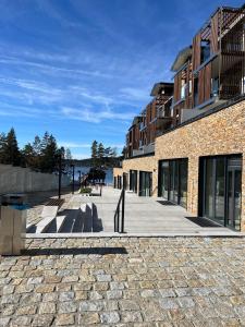 a building with a stone sidewalk next to the water at Designový apartmán Molo Lipno in Český Krumlov