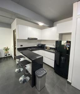 a kitchen with white cabinets and a black refrigerator at Apartamento Loft Bogotá in Bogotá