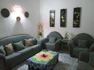 uma sala de estar com três sofás e uma mesa em Appartement Chebbi em Tozeur