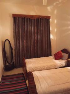 a bedroom with two beds and a window with curtains at Appartement Chebbi in Tozeur