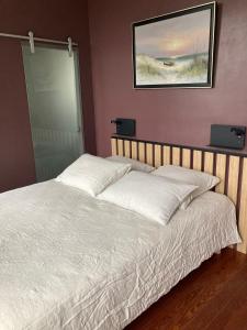 ein Bett in einem Schlafzimmer mit einem Bild an der Wand in der Unterkunft La Villa Mirabelle 2min d'Arromanches-les-Bains in Tracy-sur-Mer