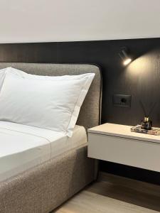 een bed met een wit kussen en een bijzettafel bij N7 apartment in Durrës