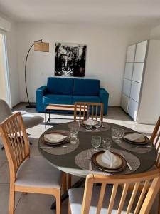 ein Wohnzimmer mit einem Tisch und einem blauen Sofa in der Unterkunft Appartement avec Terrasse in Cléon-dʼAndran