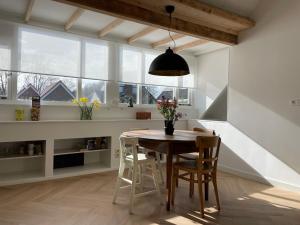 a dining room with a table and chairs and windows at Villavento in Hoofddorp